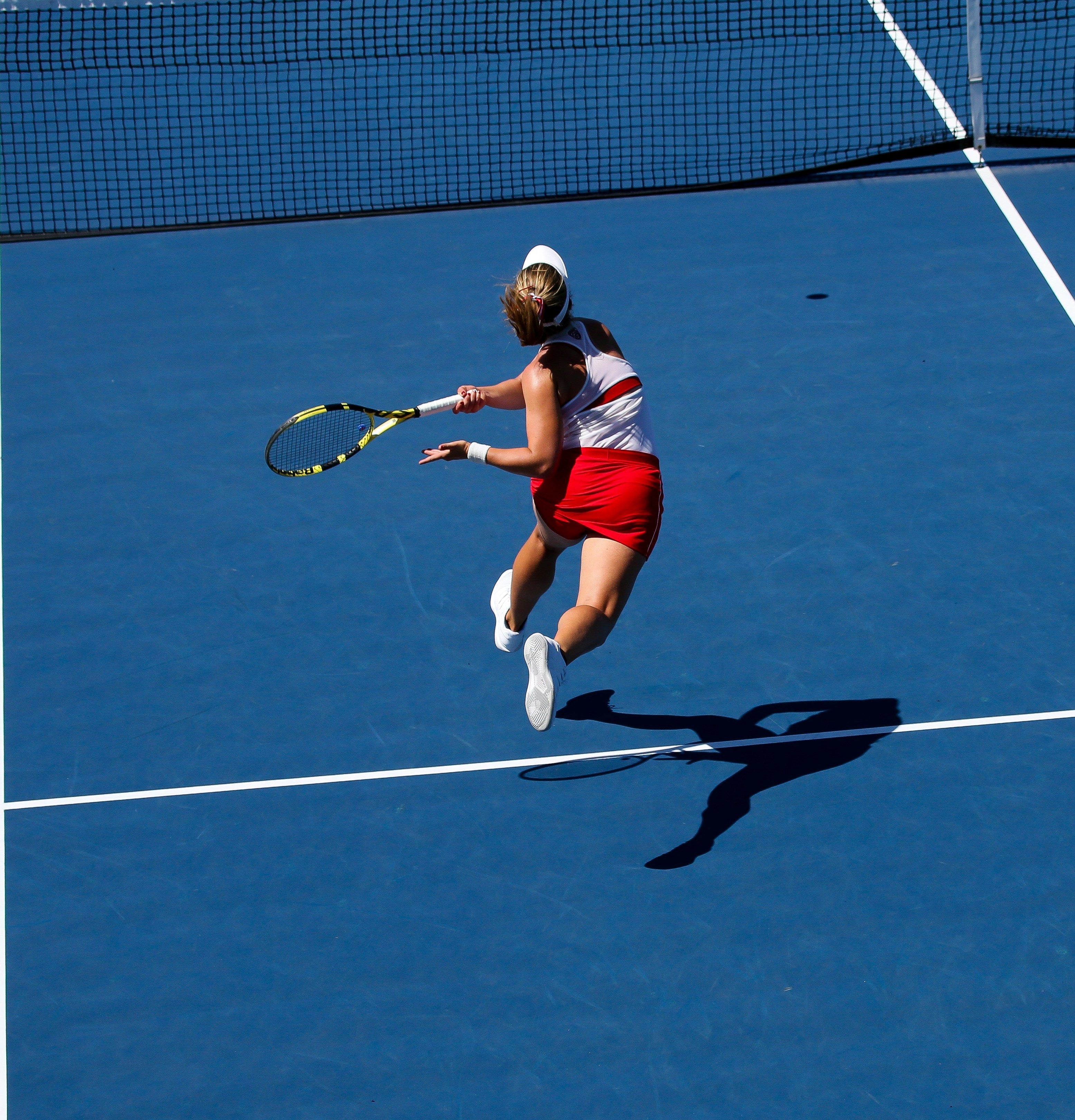 a woman playin tenis in blue tenis court